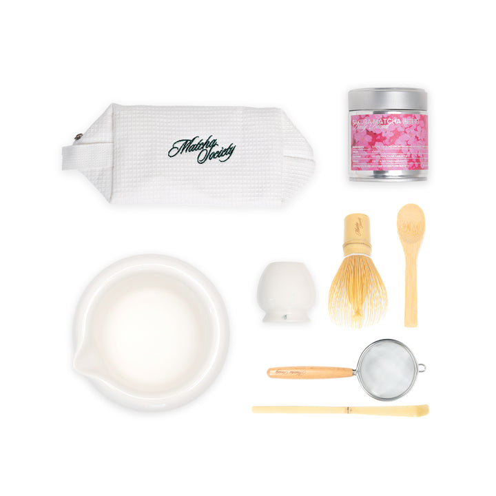 Tea-making set with a white bag, bowl, whisk, and other tools on a white background
